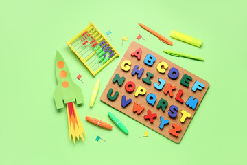 Paper rocket with abacus, wooden letters and stationery on green background