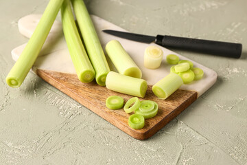 Board with fresh leeks on grey background