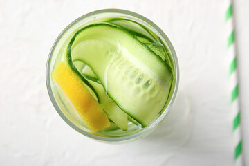 Glass of infused water with cucumber slices on white table