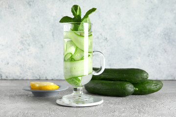 Glass of infused water with cucumber slices on grey table