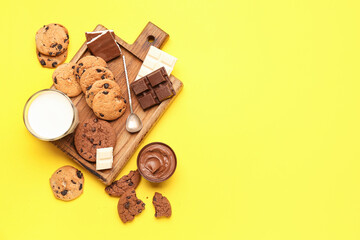 Cookies with chocolate and glass of milk on yellow background