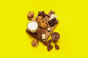 Cookies with chocolate and glass of milk on yellow background