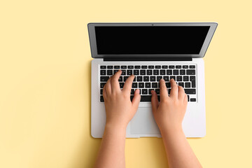 Fototapeta na wymiar Female hands with modern laptop on beige background