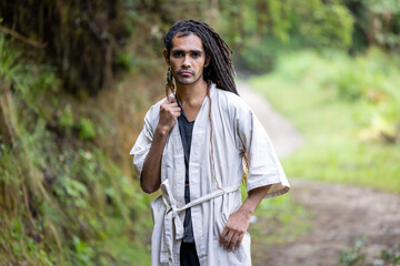 portrait of a young, attractive, dark-skinned latin man with bohemian style, hipster, fashion with dreadlocks and tunic in the woods