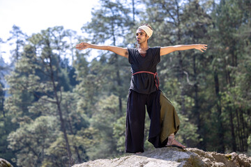 young, attractive, dark-skinned mexican latino man with bohemian style, hipster, doing yoga outdoors.