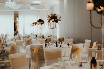 Big restaurant room with tables and chairs decorated for a wedding