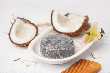 Stand with handmade solid shampoo, coconut, orchid flower and hair comb on light background, closeup