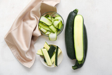 Bowls with slices of fresh zucchini on white background
