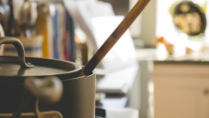 Wooden ladle in a metallic pot in a kitchen against blurred background