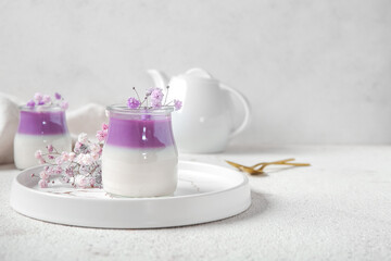 Glasses of panna cotta with beautiful gypsophila flowers and teapot on white table