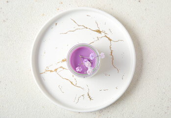 Glass of panna cotta with beautiful gypsophila flowers on white table