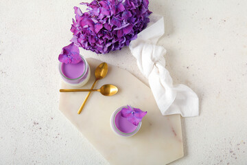 Glasses of panna cotta with beautiful hydrangea flowers on white table