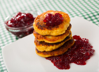 Stack of tasty fried quark pancakes served with berry jam at plate