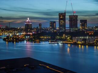 View of a river with Adam tower and modern buildings in the background in the evening, Amsterdam