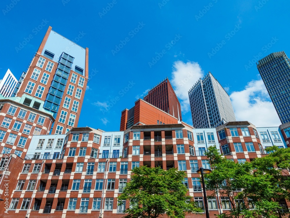 Wall mural low angle shot of modern buildings and green trees on a sunny day, rotterdam, netherlands