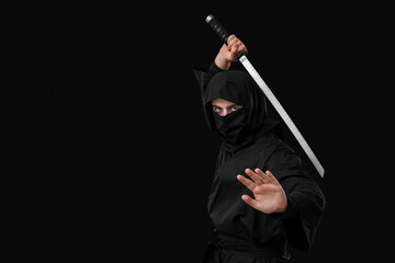 Male ninja with sword on black background