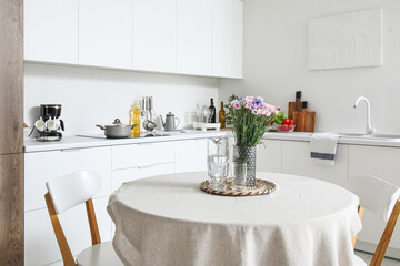 Interior of modern kitchen with flowers on dining table