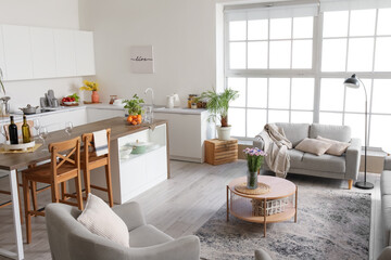 Interior of light open plan kitchen with coffee table and grey sofa
