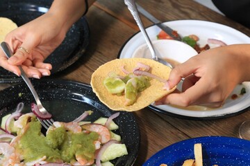 Female hand putting ingredients on bread to eat guacamole