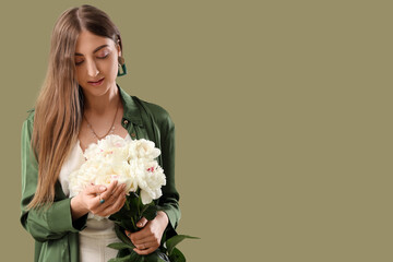 Beautiful young woman with bouquet of peony flowers on green background