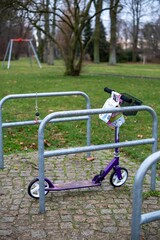 Obraz na płótnie Canvas Vertical shot of a purple scooter parked in a park