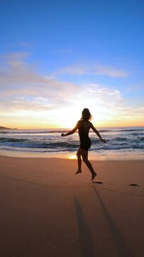 Woman is running along the beach at sunset. Florianopolis, Brazil.