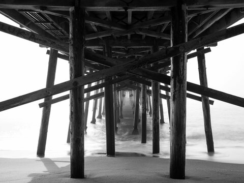 Grayscale of an sandbridge pier made of wood with supporting piles