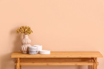 Holders with candles and flowers on table near beige wall in room