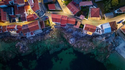 Drone shot of colorful houses on the rocky coast of Corrubedo natural park in Galicia, Spain