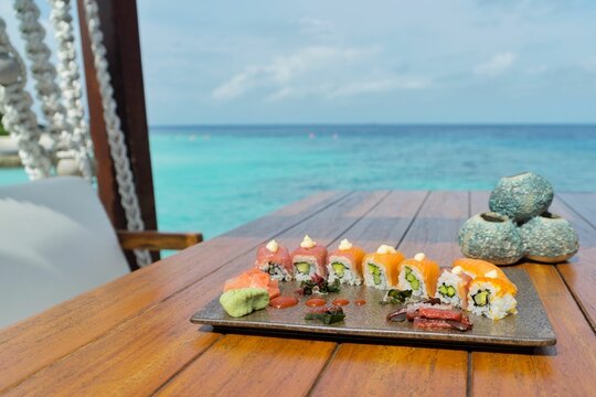 Scenic shot of sushi rolls on the wooden table on the coast of the Maldives