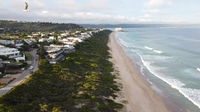 Aerial shot from above of waves on empty South African beach shoreline.