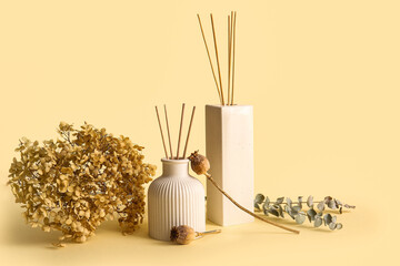 Bottles of reed diffuser, dry poppy heads and hydrangea flowers on beige background