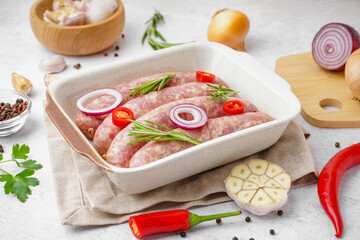 Baking dish with raw homemade sausages on light background