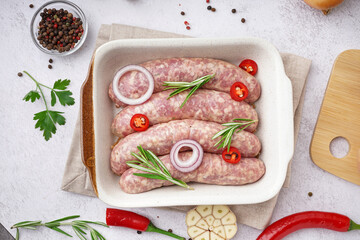 Baking dish with raw homemade sausages on light background