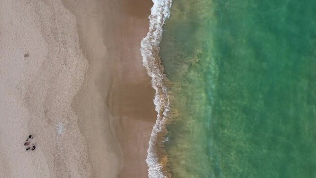 Aerial shot from above of waves on empty South African beach shoreline.