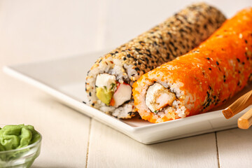 Plate with tasty sushi rolls on white wooden background, closeup