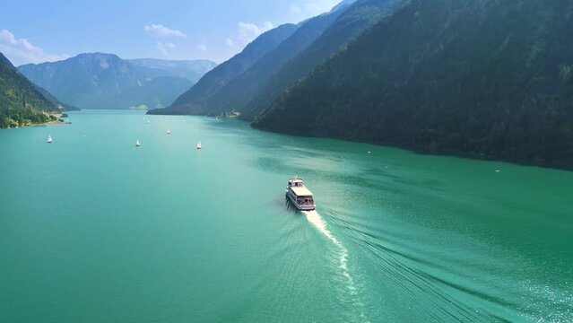 Aerial view of a boat sailing on the beautiful turquoise Lake Achen near the Alps in Austria