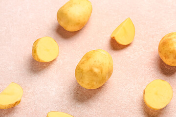 Raw baby potatoes and slices on pink background