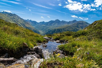 Fototapeta na wymiar Stream running through a lush green valley next to a mountain