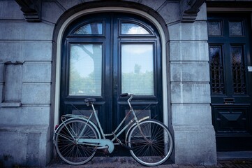 Fototapeta na wymiar Old bicycle parked on the street next to a building in daylight in Amsterdam, the Netherlands