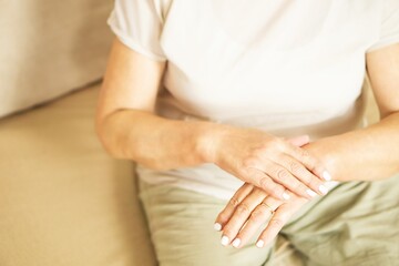 Fototapeta na wymiar Close up of a senior woman appllying hand cosmetic cream at home.