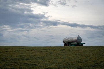 Water tanker on the field with a cloudy sky