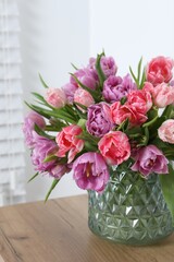 Beautiful bouquet of colorful tulip flowers on wooden table indoors