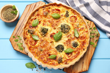 Delicious homemade vegetable quiche and seasoning on light blue wooden table, flat lay