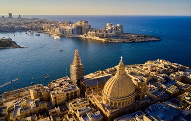 Drone shot of Valletta cityscape with St. Paul's Cathedral and the sea in Malta