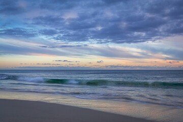 Scenic view of ocean waves crashing on the beach and a bright blue sky