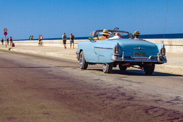 Coche clásico convertible paseando con turistas por el malecón de la habana Cuba un día soleado...