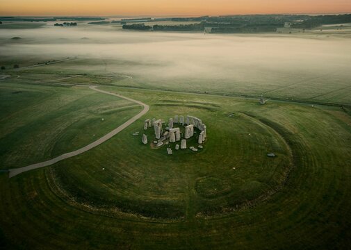 Drone shot of the Stonehenge prehistoric monument in green landscape at dusk in Wiltshire, England