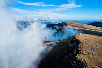 Drone view of fog and blue cloudy sky on the top of Bucegi Mountains in Romania
