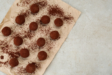 Delicious chocolate candies powdered with cocoa on light table, flat lay. Space for text
